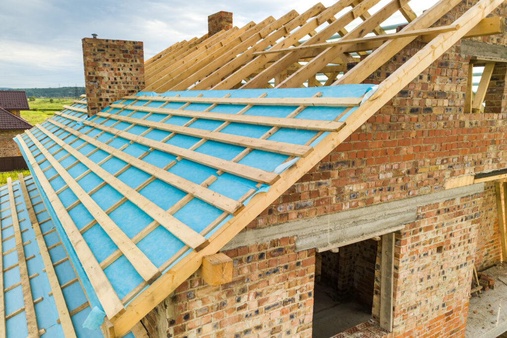 Aerial view of a brick house with wooden roof frame under constr
